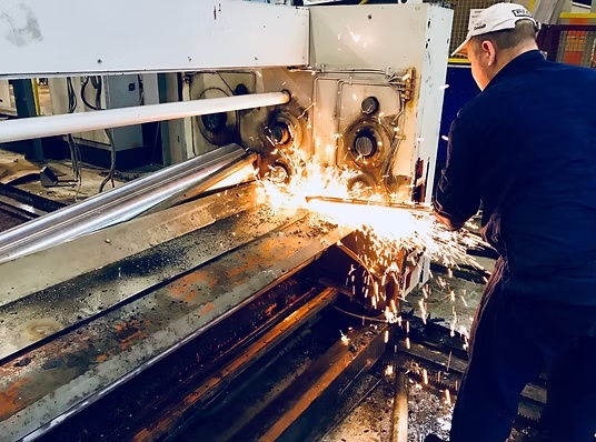 Töötaja lõikab gaasilõikajaga metallkonstruktsiooni tsehhis